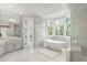 Light filled bathroom with soaking tub, glass shower, and views of the surrounding trees at 725 Riley Pl, Atlanta, GA 30327