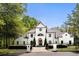 Stunning white home with manicured landscaping and black trim, enhanced by a wrought iron fence and mature trees at 725 Riley Pl, Atlanta, GA 30327