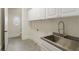 Laundry room featuring modern stainless steel sink and faucet fixtures, complemented by stylish gray tile flooring at 725 Riley Pl, Atlanta, GA 30327
