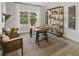 Well-lit home office with a rustic desk, comfortable seating, decorative shelves, and a view of the outdoors at 1407 Bluffs Ridge Way, Canton, GA 30114