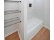 White tiled combo tub shower with black shelving and laminate flooring at 2610 Knoll Se Rd, Smyrna, GA 30080