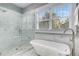Bright bathroom features a glass enclosed shower, soaking tub, and double windows at 327 6Th Ne St, Atlanta, GA 30308