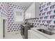 Bright laundry room features elephant wallpaper, tiled floor, white cabinets, and stainless steel washer and dryer at 327 6Th Ne St, Atlanta, GA 30308