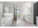 Well lit bathroom features bathtub, glass shower, and double doors to other rooms at 1600 Kamp Springs Ave, Lawrenceville, GA 30045