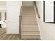 A carpeted staircase with wooden handrails leads to the upper level, next to a modern door and art at 2450 Cotton Ln, Douglasville, GA 30135