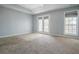 Carpeted main bedroom with tray ceiling, French doors to a balcony, and a large window with blinds at 392 Mill Pond Cossing, Carrollton, GA 30116