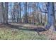 A picturesque backyard featuring a wooded area, lush grass, and a distant view of the lake at 6460 Pine Ridge Cir, Cumming, GA 30041