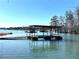 Lake house with large covered boat dock, boat lift, and dock extending into the water at 6460 Pine Ridge Cir, Cumming, GA 30041