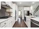 A modern kitchen features hardwood floors, white cabinets, stainless steel appliances and a gray backsplash at 224 Gallant Fox Way, Acworth, GA 30102