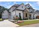 Stunning exterior showcasing a white brick and stone facade, three-car garage, and beautifully landscaped front yard at 4976 Concert Ln, Marietta, GA 30066