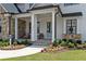Inviting front porch with stone columns, charming seating area, and a beautifully landscaped garden at 4976 Concert Ln, Marietta, GA 30066