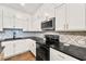 Modern kitchen featuring white cabinets, black countertops, stainless steel appliances, and tiled backsplash at 4976 Concert Ln, Marietta, GA 30066