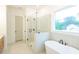 Bright bathroom featuring a glass-enclosed shower and a free-standing tub by a window at 6565 Rhett Run, Cumming, GA 30028