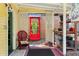 Relaxing back porch with a bright red door, colorful chair, and rustic wooden floors at 218 Barry St, Decatur, GA 30030