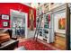 Eclectic living room features a bookshelf with ladder, red accent wall and open doorway to another room at 218 Barry St, Decatur, GA 30030