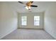 An empty room with a ceiling fan and neutral walls with two windows and carpeted floors at 2241 Nottley Dr # 4, Marietta, GA 30066