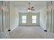 An empty room with a ceiling fan and neutral walls with two windows and carpeted floors at 2241 Nottley Dr # 4, Marietta, GA 30066