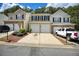 Three tan townhomes featuring a driveway with garages and green trees in the background at 2241 Nottley Dr # 4, Marietta, GA 30066
