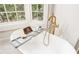 Luxurious soaking tub with gold fixtures and serene window view at 3038 Nancy Creek Nw Rd, Atlanta, GA 30327