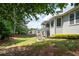 Manicured backyard with green lawn, mature trees, and a view of the home's exterior and a covered porch at 4955 Kingsbridge Ct, Powder Springs, GA 30127