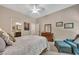 Spacious bedroom featuring a ceiling fan, a bed with patterned bedding, and an adjacent blue chaise lounge at 803 Willow Oak Dr, Woodstock, GA 30189