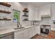 Bright kitchen features white cabinetry, stainless appliances, and open wood shelving at 803 Willow Oak Dr, Woodstock, GA 30189