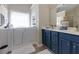 This bathroom has a walk-in tub, navy vanity with dual sinks and a window with blinds at 101 Javay Ct Ct, Villa Rica, GA 30180