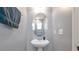 Stylish powder room with a pedestal sink, an oval mirror, and modern fixtures, offering a sleek design at 310 Oak Leaf Pl, Acworth, GA 30102
