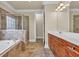 Bathroom with large tub, shower, and wood cabinets with double sinks at 3810 Baverton Dr, Suwanee, GA 30024