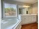 Bright bathroom features double sink vanity, bathtub and shower with natural light from a window at 72 Grayson New Hope Rd, Grayson, GA 30017
