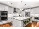 Bright, modern kitchen boasts white cabinetry, stainless steel appliances, and a large center island with hanging planters at 501 Blackberry Ln, Canton, GA 30115