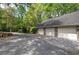 A three-car detached garage with white doors sits at the end of a long driveway lined with lush trees at 5894 Highway 20 Ne, Cartersville, GA 30121