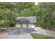 Three-car detached garage featuring brick accents and white garage doors, surrounded by lush trees at 5894 Highway 20 Ne, Cartersville, GA 30121