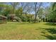 Green grass, mature trees, and partial view of an enclosed patio define the backyard landscape at 313 Ellenwood Dr, Bowdon, GA 30108