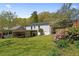 Large grassy backyard with mature landscaping, a covered carport, and a white picket fence at 313 Ellenwood Dr, Bowdon, GA 30108