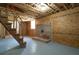 Unfinished basement showcasing exposed ceiling, brick fireplace, stairs, and a painted concrete floor at 313 Ellenwood Dr, Bowdon, GA 30108
