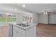 Modern kitchen island with stainless steel sink and fixtures overlooking the dining and living areas with wood floors at 313 Ellenwood Dr, Bowdon, GA 30108