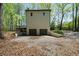 Backyard view showcasing a two car garage, deck overlooking the scenic wooded lot with lush greenery and mature trees at 7771 A C Smith Rd, Cumming, GA 30028