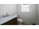 A half-bath with a toilet, window, and a vanity with a marble countertop and gold fixtures at 7771 A C Smith Rd, Cumming, GA 30028