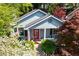 Inviting exterior view of a light blue home with a red door, surrounded by lush greenery and blooming flowers at 777 Antone Nw St, Atlanta, GA 30318