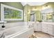 Bright bathroom with a soaking tub, vanity, and a large window overlooking greenery at 3531 Vintage Trl, Woodstock, GA 30189