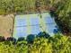 Aerial view of three well-maintained blue tennis courts surrounded by lush greenery at 3531 Vintage Trl, Woodstock, GA 30189