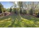 Large, well-maintained backyard with lush green grass, mature trees, and a black metal fence at 3825 Raeburn Rd, Cumming, GA 30028