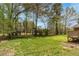 Expansive backyard featuring lush green grass, mature trees, and wooden playset at 4220 Smith Rd, Loganville, GA 30052