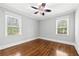 Bedroom with hardwood floors, two windows, a modern ceiling fan, and neutral colored walls at 4220 Smith Rd, Loganville, GA 30052