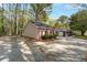 Side view of home with a one-car garage, gravel driveway, and wooded surround at 4220 Smith Rd, Loganville, GA 30052