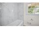 Bright bathroom featuring a bathtub with a white marble tiled wall and a window at 1830 Mayfield Rd, Alpharetta, GA 30009