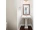 Half bath featuring a pedestal sink, wood floors, framed mirror and modern lighting at 1026 Township Sq, Alpharetta, GA 30022