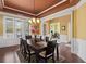 Formal dining room with elegant chandelier, wainscoting, hardwood floors, and view to the office at 3597 Old Maple Rd, Johns Creek, GA 30022