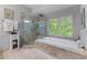 This primary bath features tile floors, a frameless shower, and a soaking tub with natural light from the window at 1180 Brookhaven Park Ne Pl, Brookhaven, GA 30319